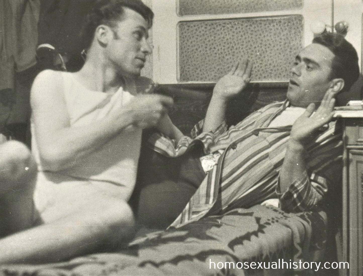 Bulgaria 1950s. Two playful men on bed 1 of 2