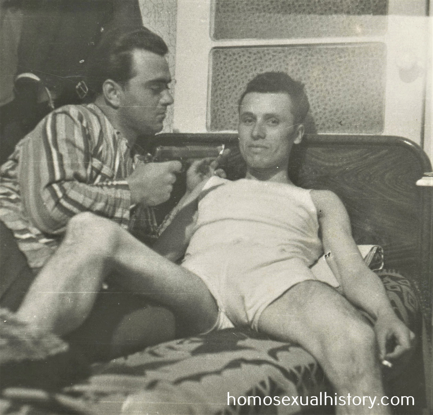 Bulgaria 1950s. Two playful men on bed 2 of 2